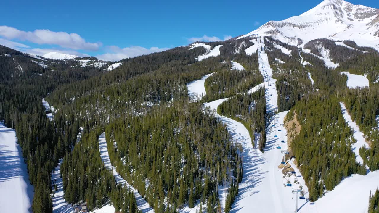 Drone captures winter activity at Big Sky, Montana, with skiers riding chair lifts and slicing down snow-covered slopes surrounded by frosty trees and wide-open alpine ski terrain
