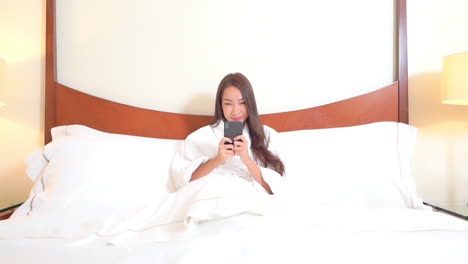 beautiful young woman in bedroom checking social networks on bright morning