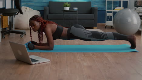 mujer flexible de piel negra con ropa deportiva practicando ejercicios deportivos de yoga