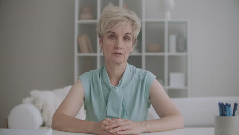 videocall of aged woman by internet portrait shot in home lady is talking to camera sitting at table