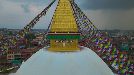 Boudha-Stupa-Nepal,-Drone-Close-up-Reveals-UNESCO-Heritage-Site,-landscape-of-Kathmandu-city,-clouds-and-sky,-Stupa-Buddha-eye-4K