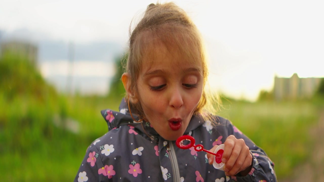 Giovane ragazza con apparecchio acustico che fa bolle di sapone all'aperto