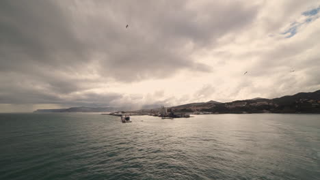 Cruise-ship-leaving-the-beautiful-italian-harbour-of-Savona,-with-seagulls-flying-around