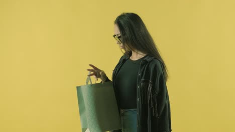 joven hermosa con bolsas de compras en el fondo amarillo