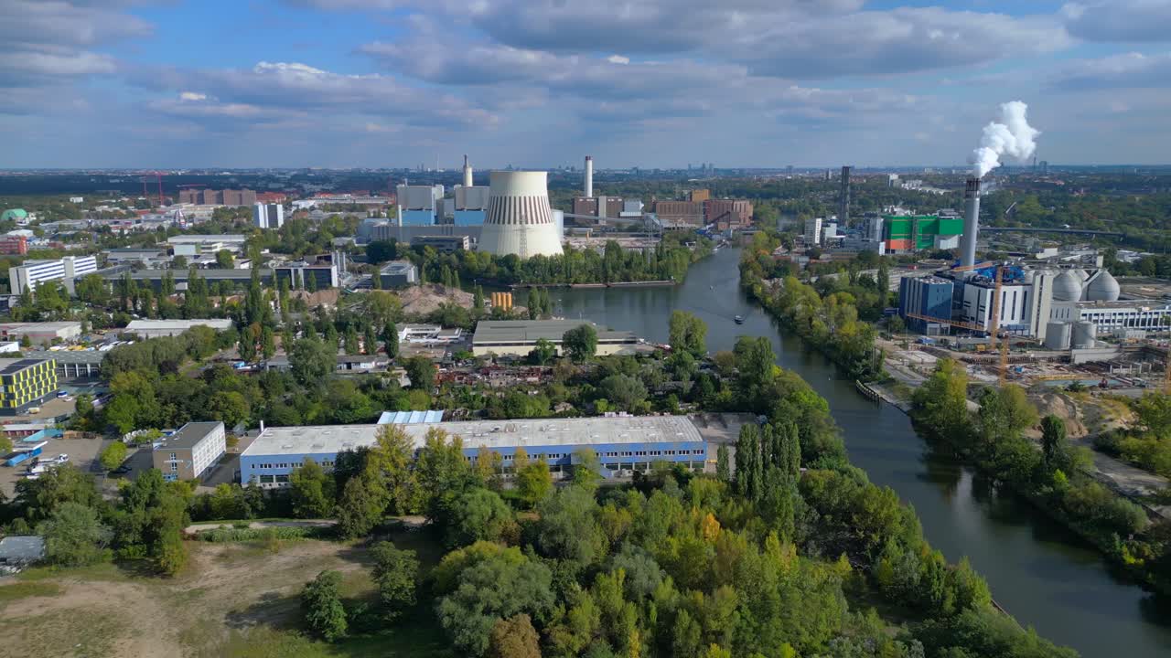 Industrial landscape with factories, a large power plant, and storage tanks bordering river in berlin germany. Amazing aerial view flight rotation pan to right drone