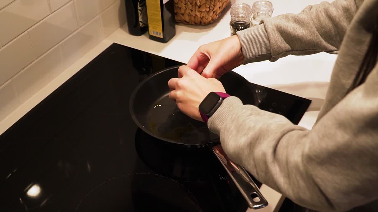 Woman hands break egg and cooking the scrambled eggs on the frying pan