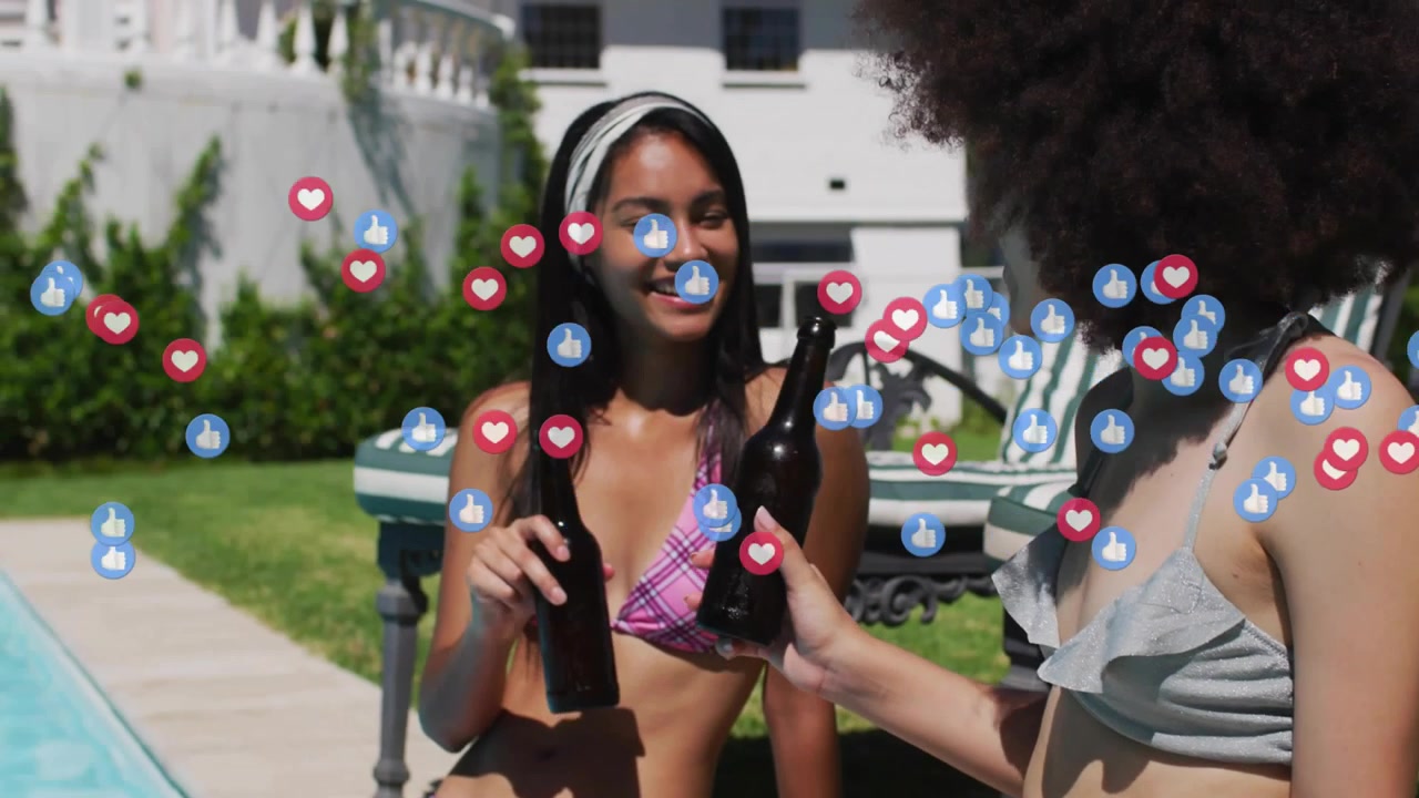 Two women lifting beer bottles for toast beside pool, initiating social media reactions swirling