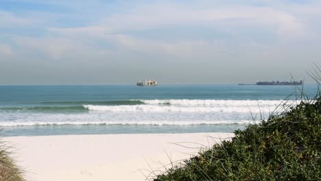 serene beach scene with cargo ships on the horizon