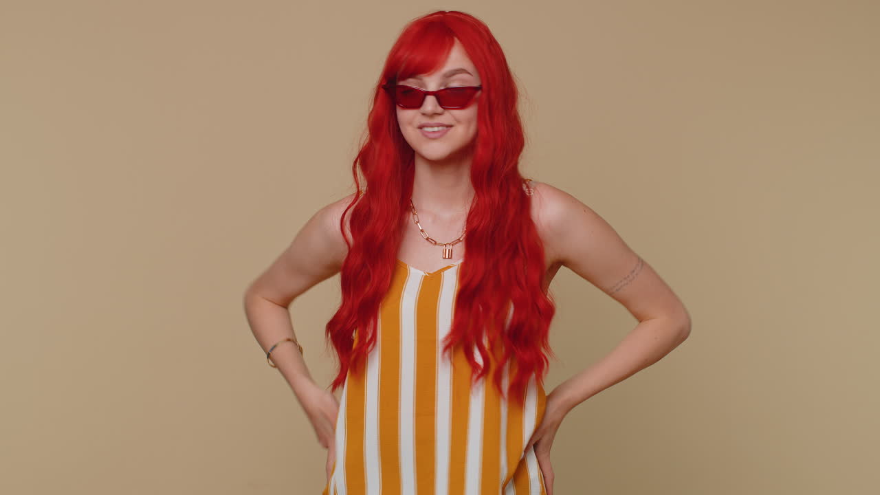 매혹적인 쾌활한 은색 스타일의 소녀 크 을 입고 선글라스를 입고, 베이지 벽에 매력적인 미소를 짓고