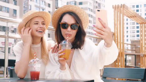 two friends enjoying drinks and taking a selfie outdoors