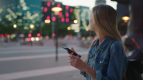 portrait-of-attractive-blonde-woman-taking-photo-of-city-lights-using-smartphone-camera-technology-wearing-earphones-listening-to-music