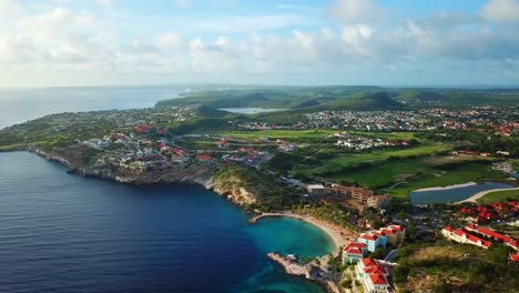 Aerial-view-dolly-in-of-Curacao's-largest-beach,-Blue-Bay,-cloud-filled-horizon