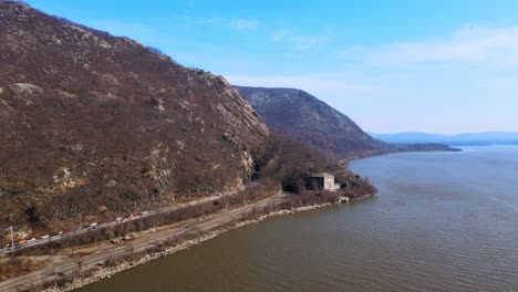 Aerial-drone-footage-flying-alongside-the-Appalachian-mountains-over-a-river-in-new-york's-hudson-valley-during-early-spring-at-breakneck-ridge-and-the-hudson-river