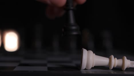 close-up of a chessboard as a player knocks over the king, winning the game