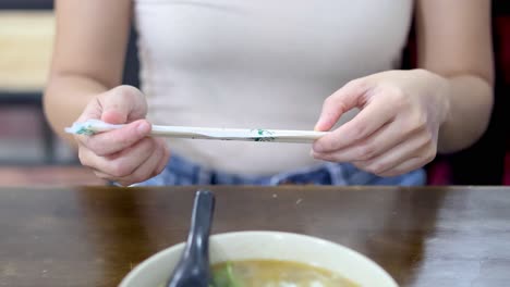 persona desempaquetando palillos antes de comer sopa