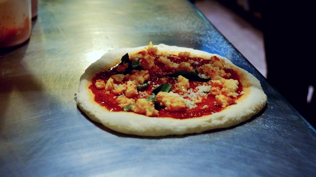 Autentico processo di preparazione della pizza in una pizzeria tradizionale italiana, con lo chef che aggiunge i condimenti sulla pizza