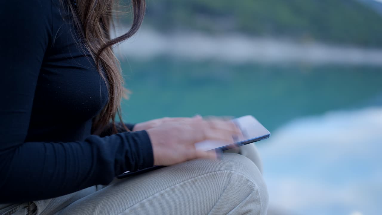 Woman using a tablet by the lake