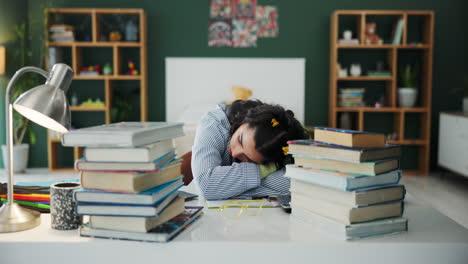 tired student sleeping at her desk surrounded by books