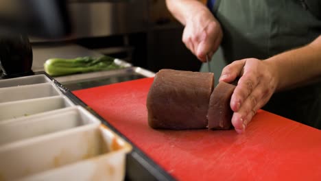 chef cuts slice of tuna with knife