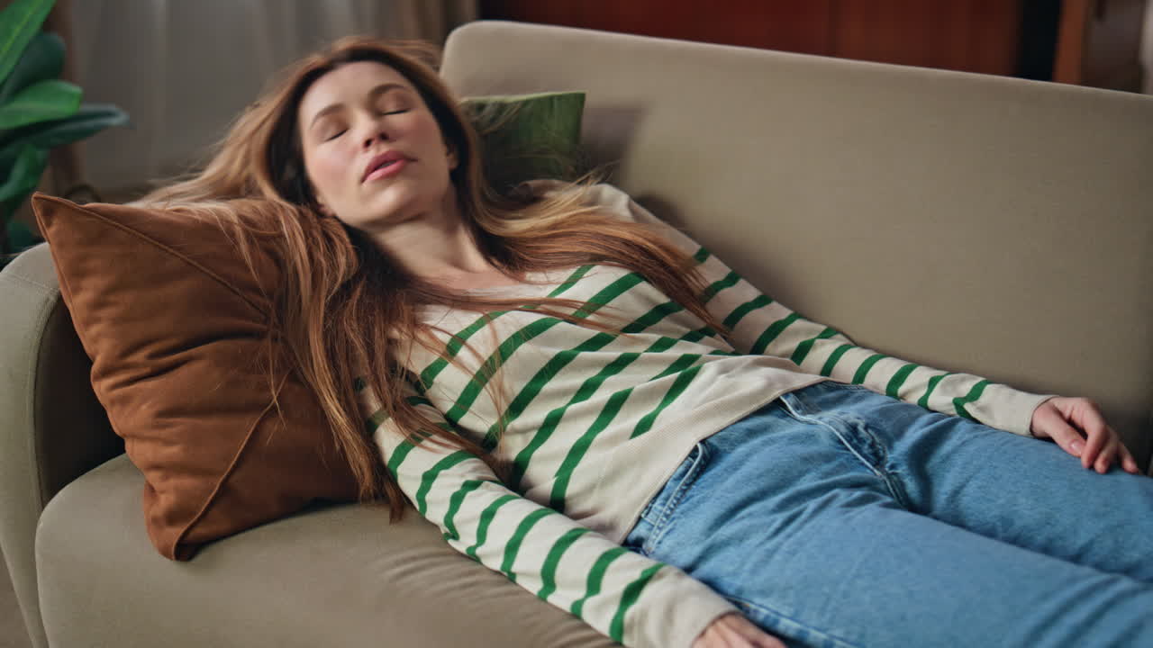 Fatigued woman falling sofa holding cellphone close up. Lady lying couch texting