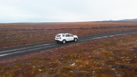 suv car driving slowly on wet gravel road with puddles in foggy heath