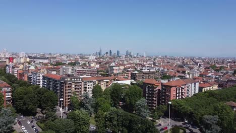 apartment buildings and milan city skyline in distance, aerial fly forward view