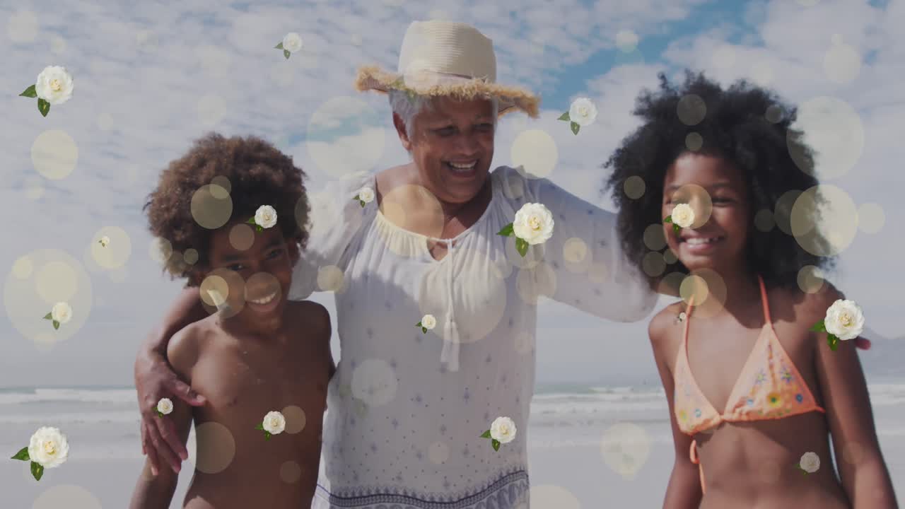 Animazione di punti e fiori su una felice nonna afroamericana e nipoti in spiaggia