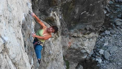 bird'seye shot of a rock climber struggling to pull herself up a cliff wall