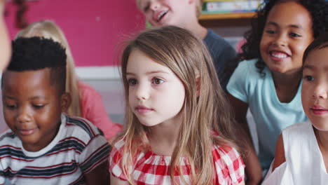 group of elementary school pupils sitting on floor listening to teacher