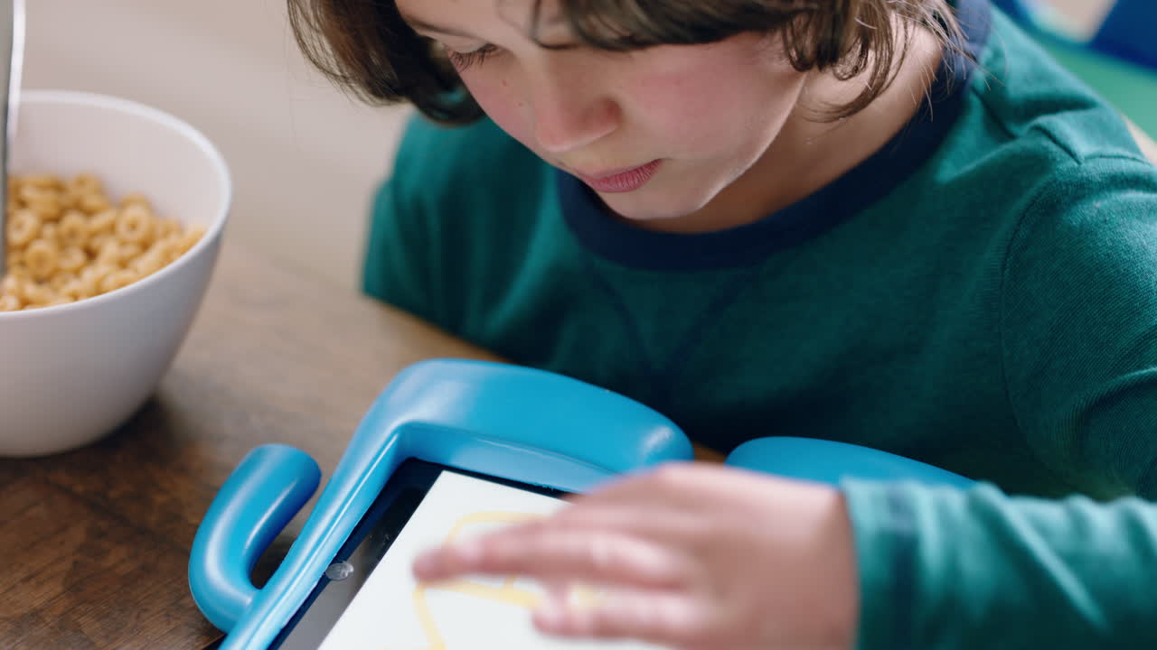 niño usando una tableta digital un niño pequeño jugando a juegos divirtiéndose aprendiendo en la tecnología de pantalla táctil en casa en el desayuno