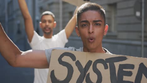 dos hombres de raza mixta en una marcha de protesta con pancartas levantando las manos y gritando