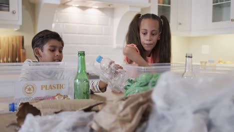 happy biracial brother and sister segregating waste in kitchen, slow motion