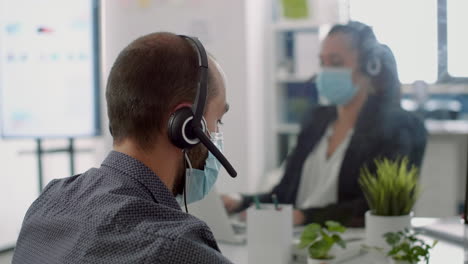 Business-team-wearing-protective-face-masks-and-headphone