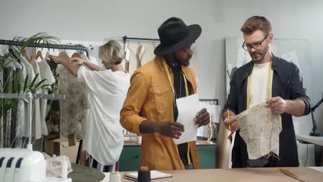 young and clothing designers working together while a female designer chooses a cloth and shows it to them