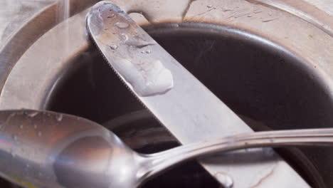 spoon adn knife inse sink while running water on sink