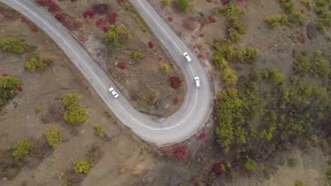 cars go on turn of serpentine mountain road. aerial vertical top view. drone is rotating