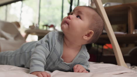 cute asian mixed race baby doing tummy time in play gym