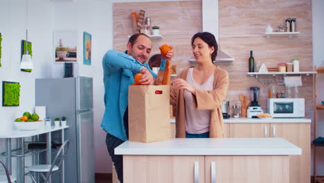 un chico hace malabarismos con su esposa en la cocina.