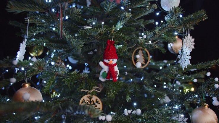 Hanging Snowman Decoration on Green Christmas Tree Dark