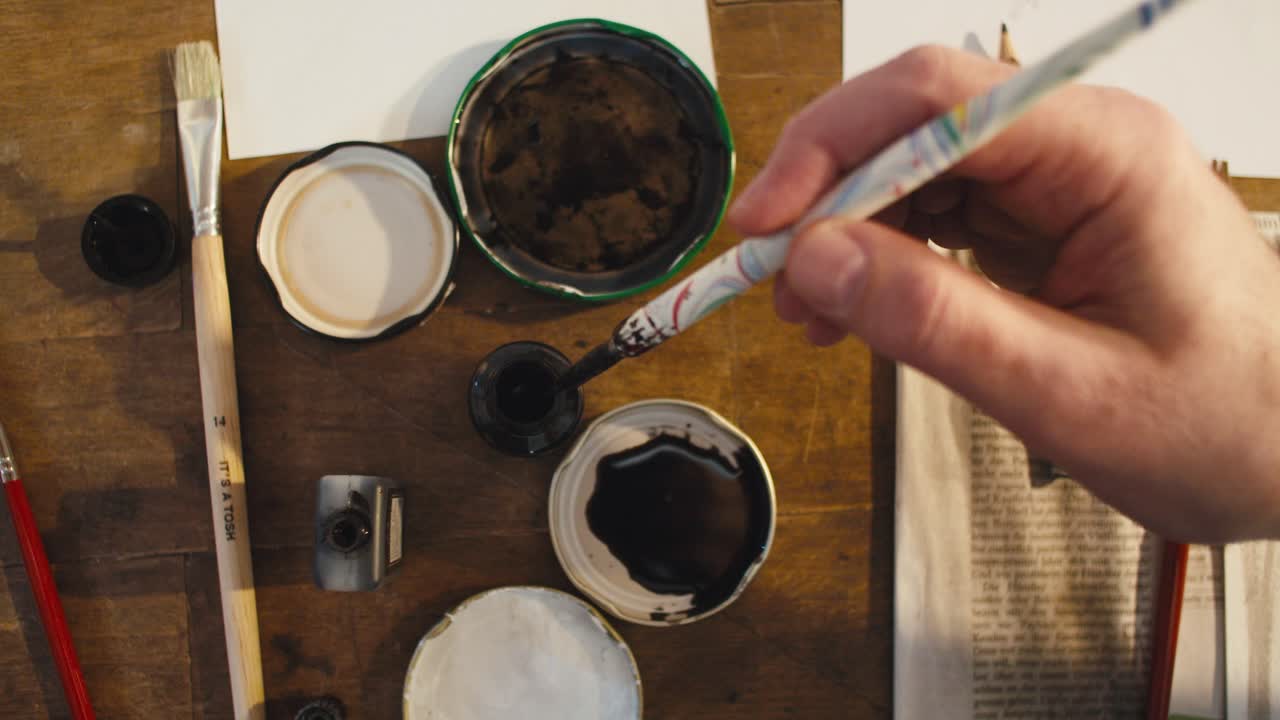 artista masculino sumergiendo un bolígrafo en tinta, vista desde arriba