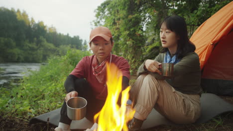 female tourists resting by campfire and talking