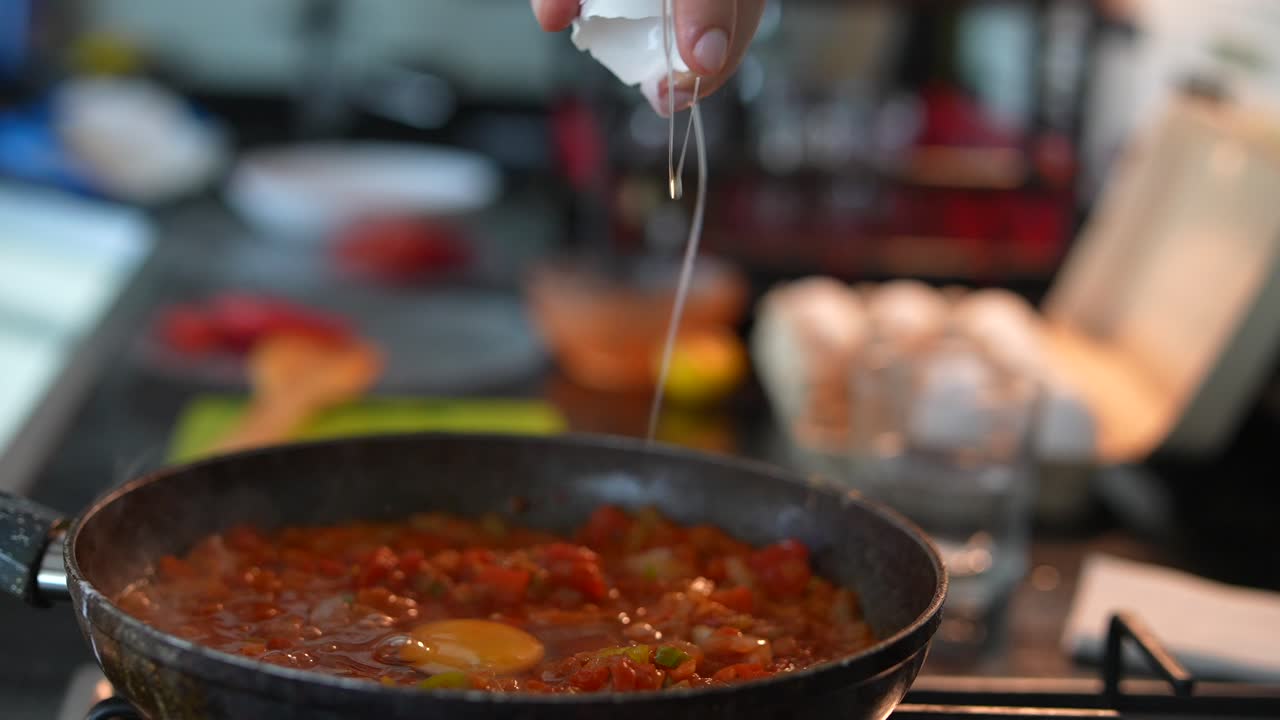 cocinando un huevo con tomates en una sartén