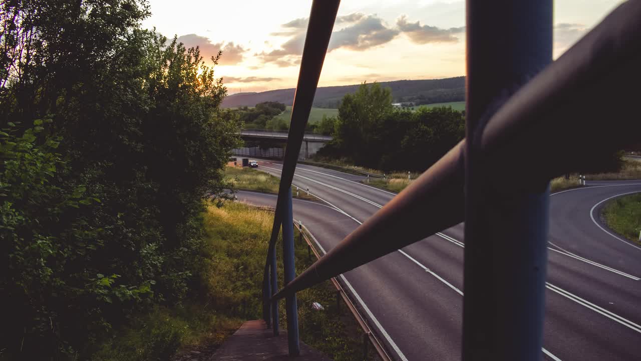 Zeitraffer von Autos auf einer Autobahn mit wunderschönem Sonnenuntergang im Hintergrund in Deutschland