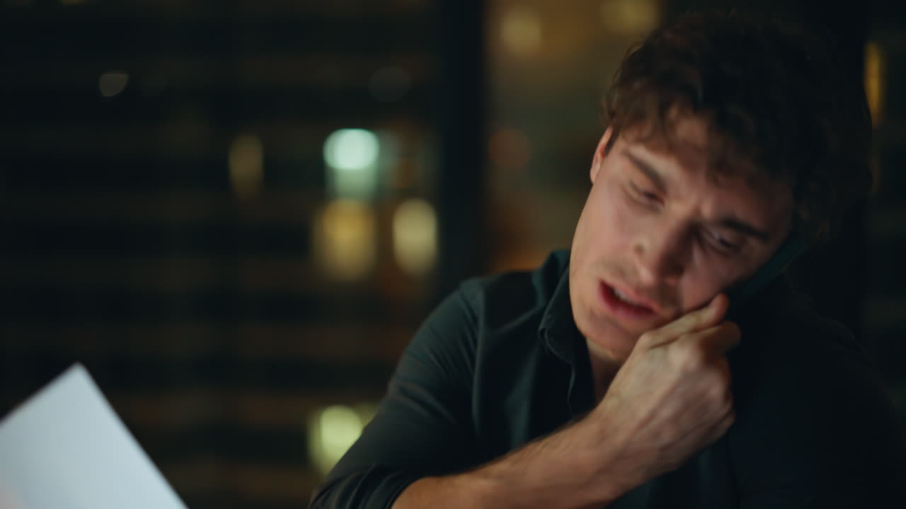 Furious boss complaining cellphone call throwing papers at night office closeup