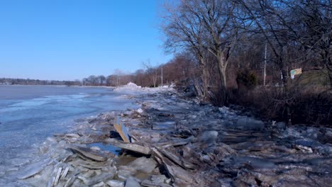 Vuelo-Lento-De-Drones-A-Lo-Largo-Del-Borde-De-Un-Río-Congelado-Con-Muchos-Escombros-Rotos-Incrustados-En-El-Hielo-Roto-A-Lo-Largo-Del-Borde-Del-Río