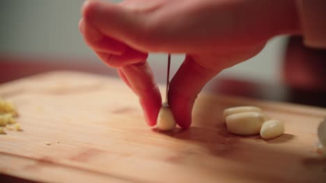 cortar dientes de ajo a mano con un cuchillo en una tabla de cortar