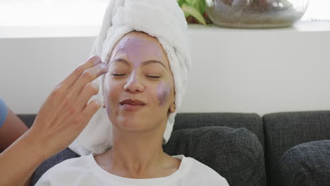 young biracial woman applies facial mask at home, with copy space