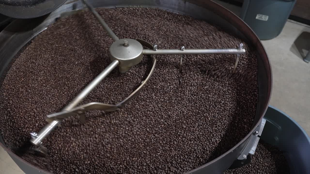 Coffee beans being stirred in a moving cooling drum after roasting