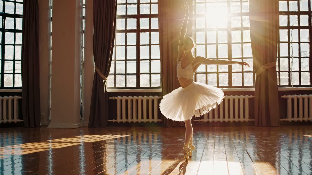 Un video ritrae una ballerina in uno studio illuminato dal sole, ripresa da una bassa angolazione, che ne mette in risalto la grazia