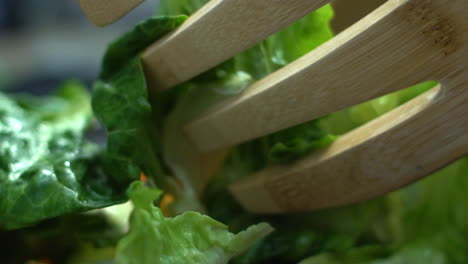 un primerísimo plano de ensalada de madera manos mezclando ensalada